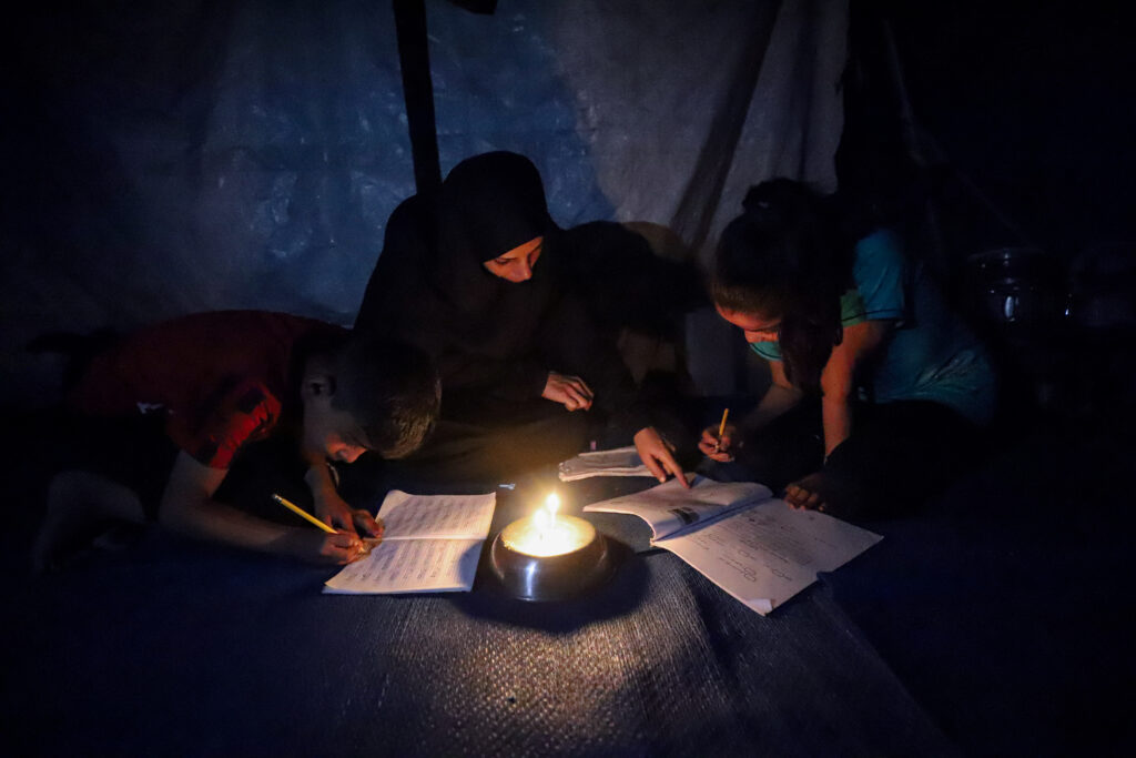 Gazze’de yerinden edilen öğrenciler, ödevlerini mum ışığında yapıyor