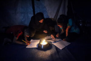 Gazze’de yerinden edilen öğrenciler, ödevlerini mum ışığında yapıyor